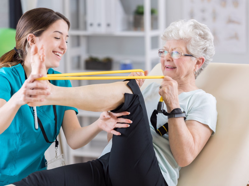 Fisioterapeuta auxiliando uma idosa em exercícios de reabilitação