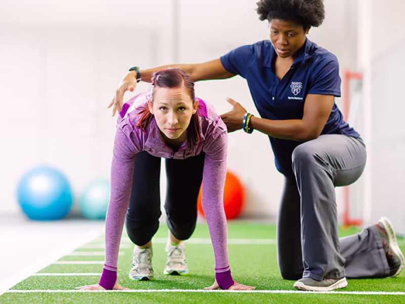 Fisioterapeuta auxiliando um atleta em exercícios de treinamento esportivo
